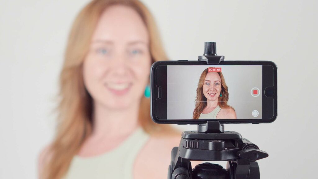 Frau erstellt ein Video von sich mit einem Smartphone auf dem Stativ