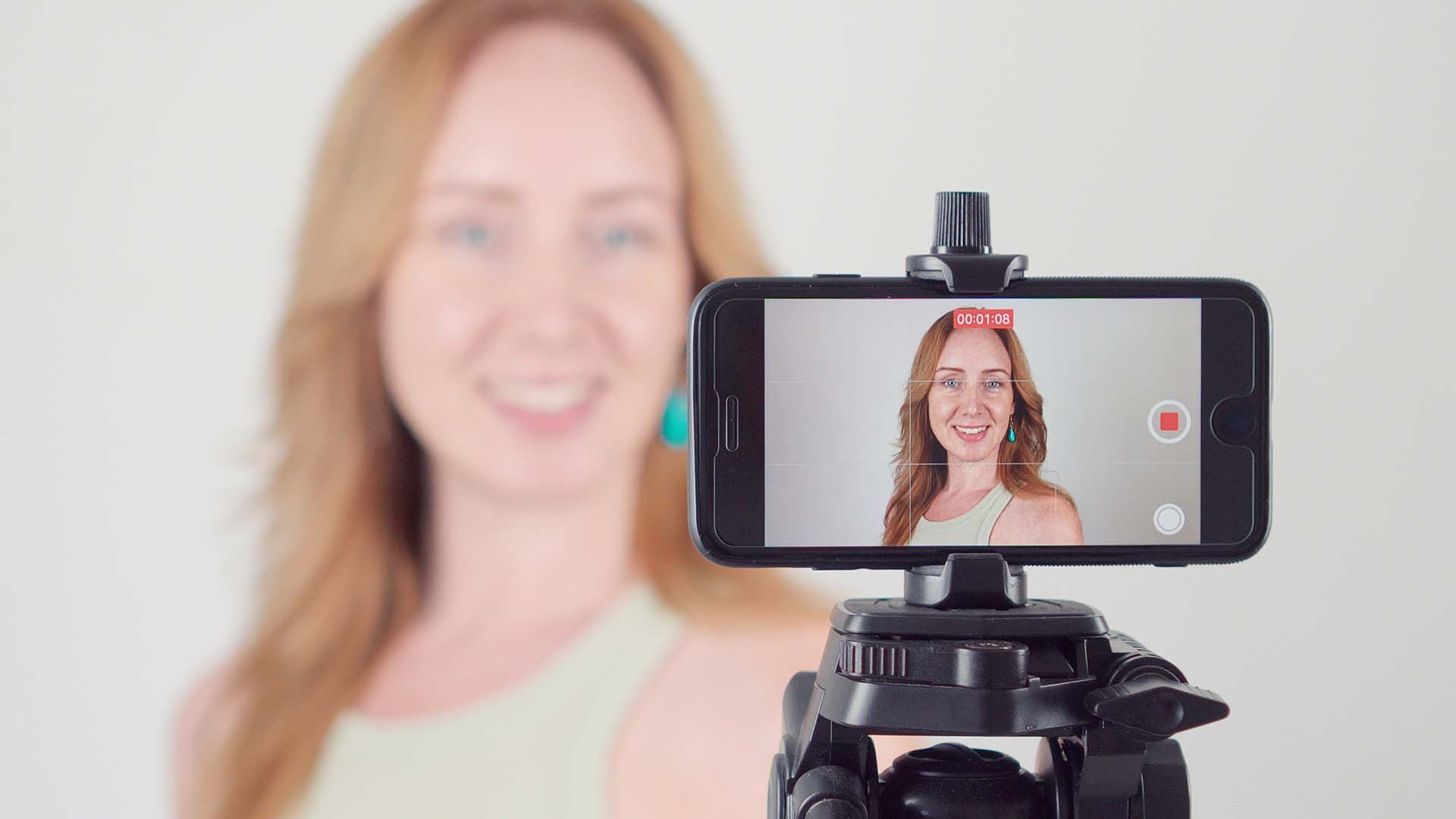 Frau erstellt ein Video von sich mit einem Smartphone auf dem Stativ